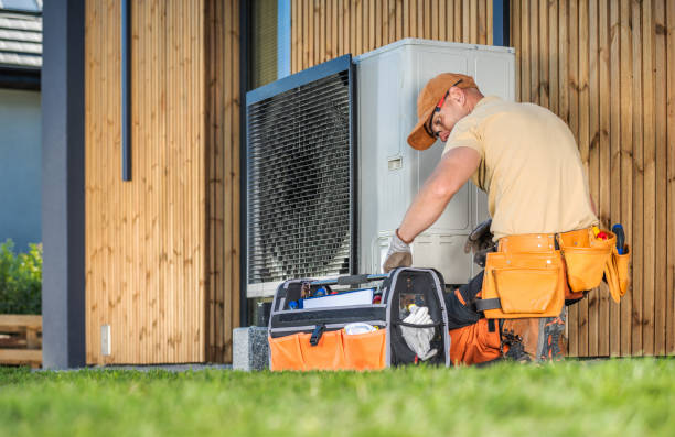 hvac worker working on a modern heat pump outside a house. hvac worker working on a modern heat pump outside a house.